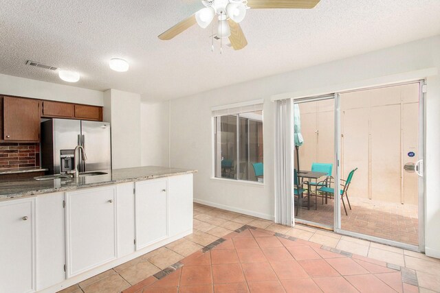 11625 Lakeside Park Dr, Houston, TX 77077 - kitchen featuring stainless steel fridge, light tile patterned floors, a ceiling fan, a textured ceiling, and light stone counters