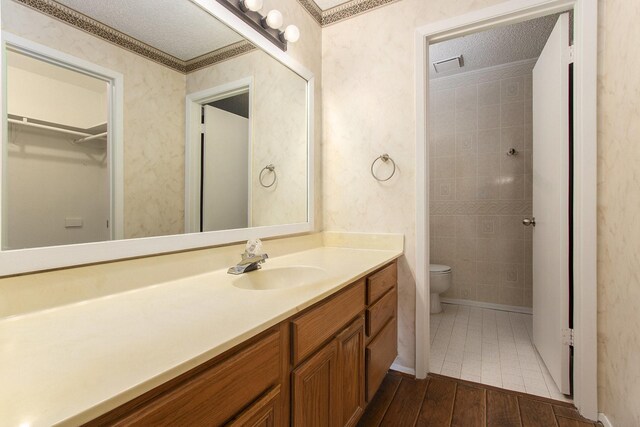 11625 Lakeside Park Dr, Houston, TX 77077 - full bath with vanity, wood finished floors, a walk in closet, and a textured ceiling