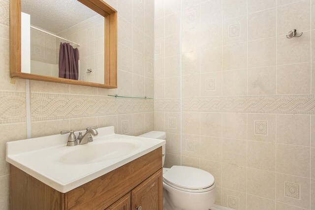 11625 Lakeside Park Dr, Houston, TX 77077 - full bathroom featuring vanity, tile walls, a shower with curtain, and a textured ceiling
