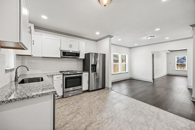 102 Glendale St, Houston, TX 77012 - kitchen featuring appliances with stainless steel finishes, a sink, light stone counters, crown molding, and baseboards