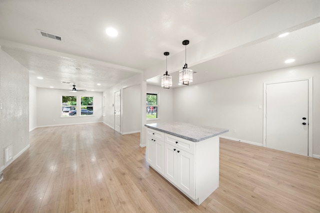 5607 Flamingo Dr, Houston, TX 77033 - kitchen featuring open floor plan, a center island, white cabinets, light wood finished floors, and hanging light fixtures