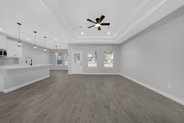 2506 Myrtle St, Waller, TX 77484 - unfurnished living room featuring ceiling fan, recessed lighting, a raised ceiling, dark wood-style flooring, and baseboards