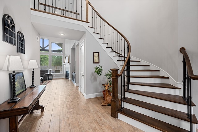 13630 E Palomino Lake Cir, Cypress, TX 77429 - stairs with baseboards, wood finished floors, a high ceiling, and a glass covered fireplace