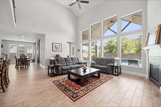 13630 E Palomino Lake Cir, Cypress, TX 77429 - living room featuring a ceiling fan, plenty of natural light, high vaulted ceiling, a tiled fireplace, and baseboards