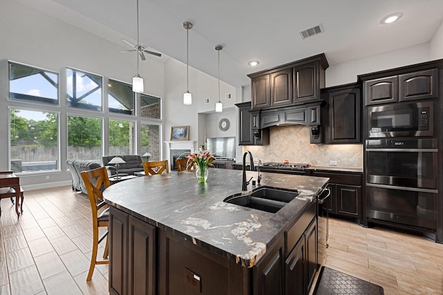 13630 E Palomino Lake Cir, Cypress, TX 77429 - kitchen featuring stainless steel oven, built in microwave, tasteful backsplash, a ceiling fan, and dark stone countertops