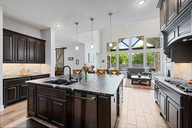 13630 E Palomino Lake Cir, Cypress, TX 77429 - kitchen with appliances with stainless steel finishes, a sink, a barn door, tasteful backsplash, and a kitchen island with sink