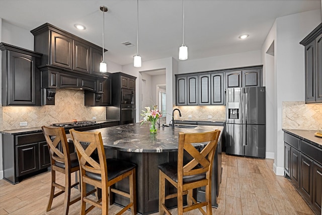 13630 E Palomino Lake Cir, Cypress, TX 77429 - kitchen featuring stainless steel fridge with ice dispenser, a sink, black oven, tasteful backsplash, and dark countertops
