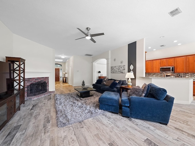24602 Windemere Park Ct, Katy, TX 77494 - living area featuring arched walkways, light wood-style flooring, ceiling fan, a fireplace, and recessed lighting