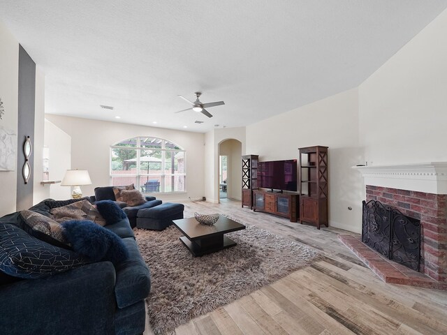 24602 Windemere Park Ct, Katy, TX 77494 - living room featuring arched walkways, wood finished floors, a ceiling fan, a fireplace, and recessed lighting