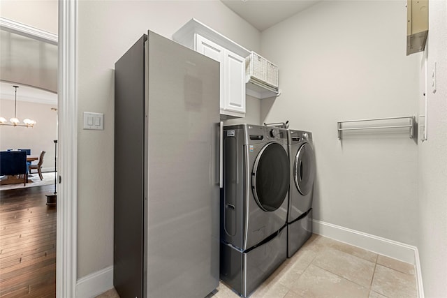 119 W Valera Ridge Pl, Spring, TX 77389 - washroom featuring washing machine and dryer, baseboards, a chandelier, cabinet space, and light tile patterned floors