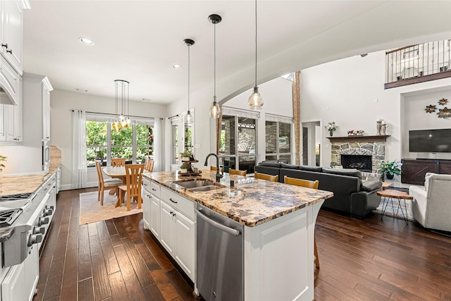 119 W Valera Ridge Pl, Spring, TX 77389 - kitchen with stainless steel dishwasher, a sink, dark wood-style floors, a stone fireplace, and recessed lighting