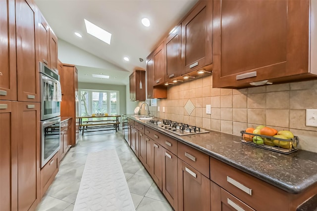23011 Grand Rapids Ln, Spring, TX 77373 - kitchen with appliances with stainless steel finishes, lofted ceiling, backsplash, dark stone counters, and a sink