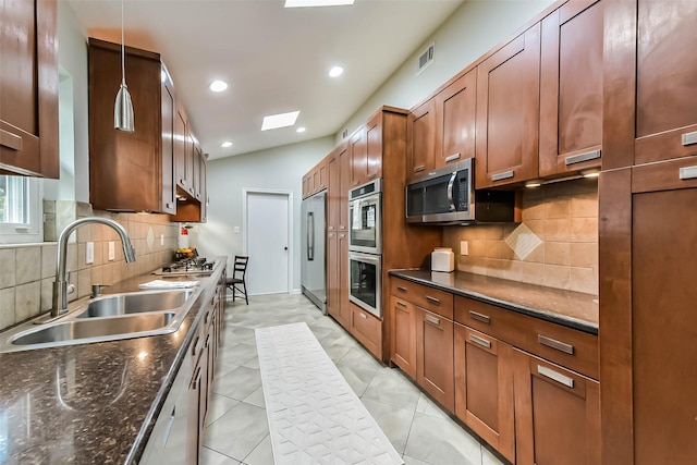 23011 Grand Rapids Ln, Spring, TX 77373 - kitchen featuring a sink, stainless steel appliances, tasteful backsplash, brown cabinetry, and dark stone countertops