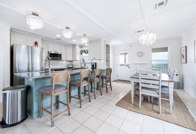 1197 County Road 230, Sargent, TX 77414 - kitchen with appliances with stainless steel finishes, a chandelier, open shelves, a breakfast bar, and light tile patterned flooring