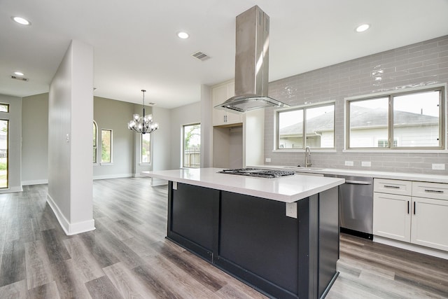 3337 Shelby Cir, Houston, TX 77051 - kitchen featuring island exhaust hood, backsplash, a center island, white cabinetry, and stainless steel appliances