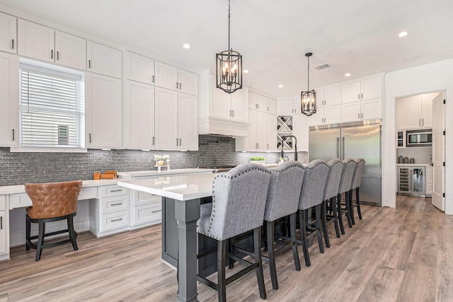 111 Seagull Path, Point Blank, TX 77364 - kitchen with built in appliances, beverage cooler, light countertops, a breakfast bar, and white cabinets