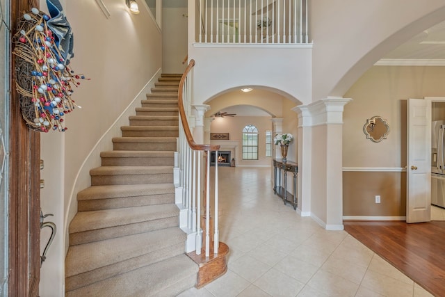 31335 Bearing Star Ln, Tomball, TX 77375 - foyer with arched walkways, light tile patterned floors, decorative columns, a lit fireplace, and a high ceiling
