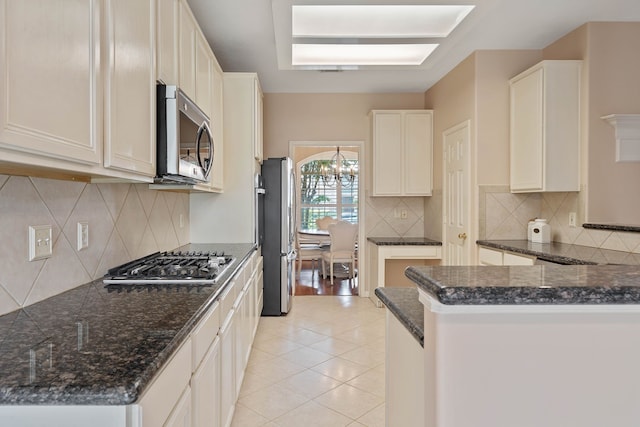 31335 Bearing Star Ln, Tomball, TX 77375 - kitchen with appliances with stainless steel finishes, a chandelier, backsplash, light tile patterned floors, and dark stone counters