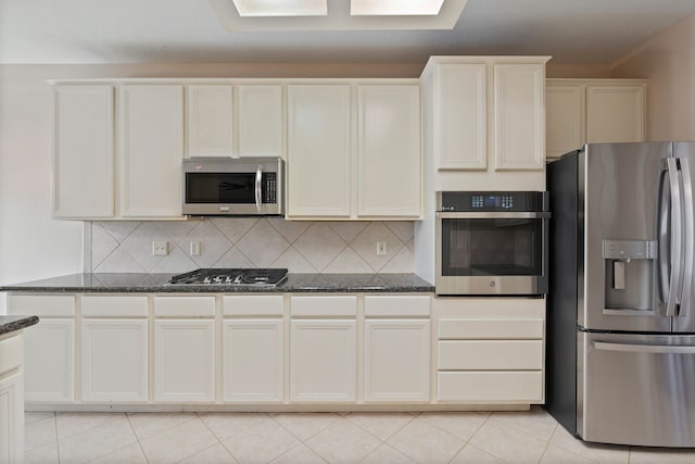 31335 Bearing Star Ln, Tomball, TX 77375 - kitchen with appliances with stainless steel finishes, dark stone countertops, light tile patterned floors, and decorative backsplash