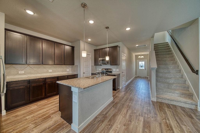 22168 Juniper Crossing Dr, New Caney, TX 77357 - kitchen with stainless steel appliances, light wood-style floors, a sink, dark brown cabinets, and recessed lighting