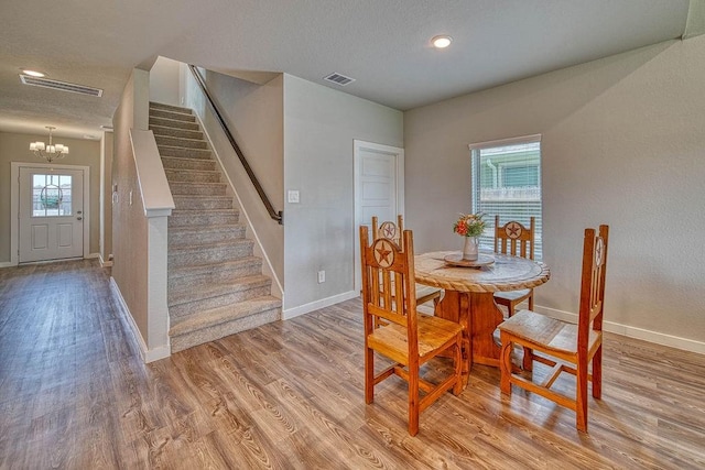 22168 Juniper Crossing Dr, New Caney, TX 77357 - dining space featuring stairway, baseboards, a chandelier, light wood-style flooring, and a textured ceiling