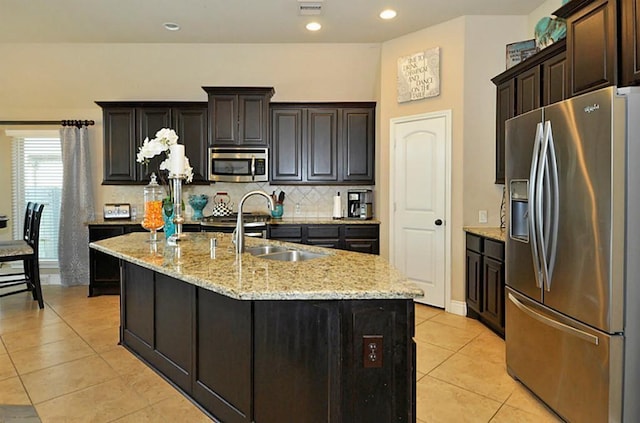 22419 Slate Oaks Ln, Richmond, TX 77469 - kitchen featuring appliances with stainless steel finishes, a sink, tasteful backsplash, light tile patterned floors, and a kitchen island with sink