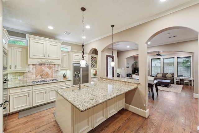 1215 Malone St, Houston, TX 77007 - kitchen featuring arched walkways, appliances with stainless steel finishes, a sink, light stone counters, and decorative backsplash
