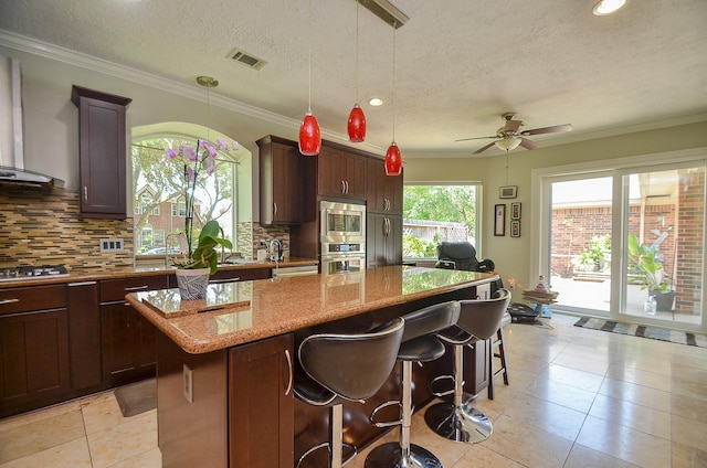 7103 Adobe Meadows Ct, Sugar Land, TX 77479 - kitchen featuring a kitchen island, light stone counters, ceiling fan, backsplash, and stainless steel appliances