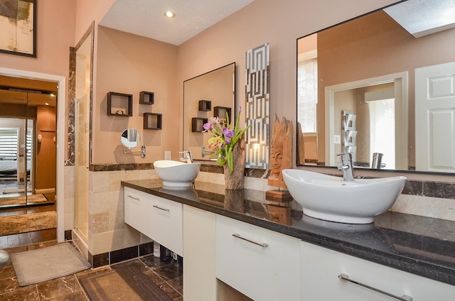 7103 Adobe Meadows Ct, Sugar Land, TX 77479 - bathroom featuring a stall shower, double vanity, marble finish flooring, tile walls, and recessed lighting