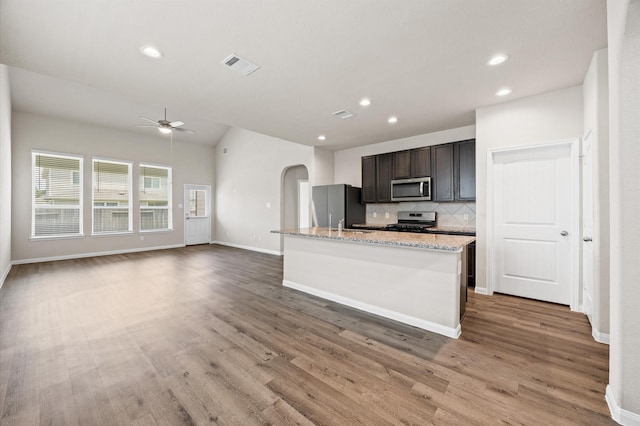 14008 Paddlefish Dr, Conroe, TX 77384 - kitchen with stainless steel appliances, ceiling fan, arched walkways, tasteful backsplash, and light wood-style floors