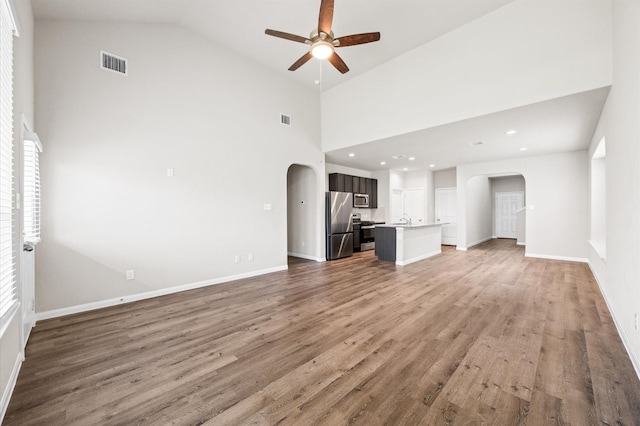 14008 Paddlefish Dr, Conroe, TX 77384 - unfurnished living room featuring arched walkways, a ceiling fan, high vaulted ceiling, wood finished floors, and recessed lighting