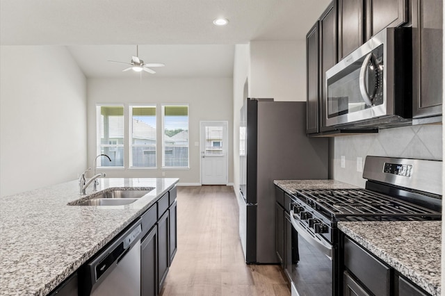 14008 Paddlefish Dr, Conroe, TX 77384 - kitchen with stainless steel appliances, light wood-style flooring, light stone countertops, ceiling fan, and tasteful backsplash