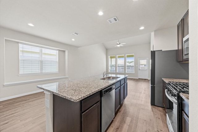 14008 Paddlefish Dr, Conroe, TX 77384 - kitchen with stainless steel appliances, light wood-type flooring, light stone counters, dark brown cabinetry, and ceiling fan