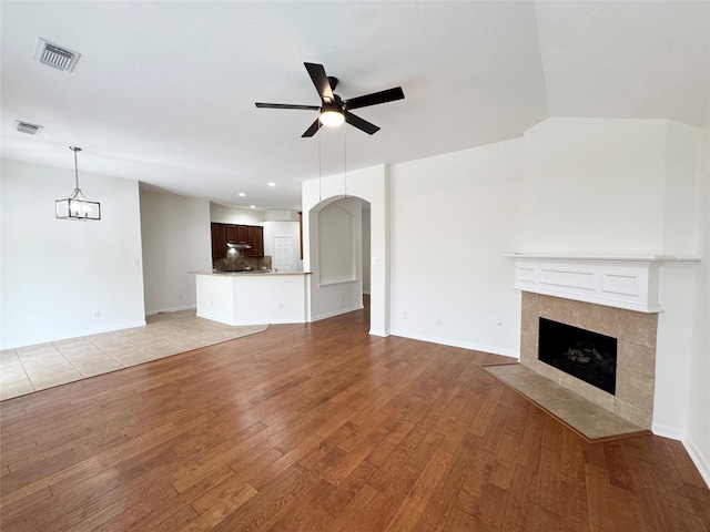 30611 Pinemill Hollow Dr, Spring, TX 77386 - unfurnished living room featuring a ceiling fan, light wood finished floors, a fireplace, arched walkways, and baseboards