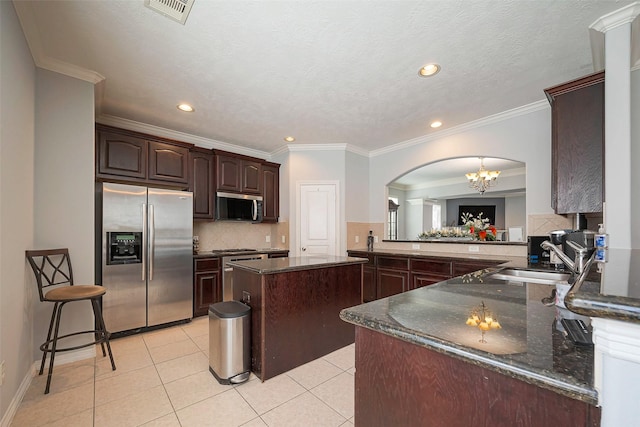 3426 Skyline Village Dr, Houston, TX 77057 - kitchen with appliances with stainless steel finishes, arched walkways, a sink, dark brown cabinets, and decorative backsplash