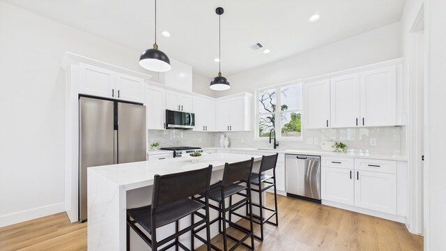 1813 Brooks St, Houston, TX 77026 - kitchen with appliances with stainless steel finishes, decorative backsplash, light countertops, white cabinets, and light wood-style flooring