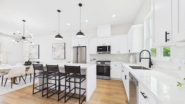1813 Brooks St, Houston, TX 77026 - kitchen featuring appliances with stainless steel finishes, a sink, a center island, light wood-style floors, and white cabinetry