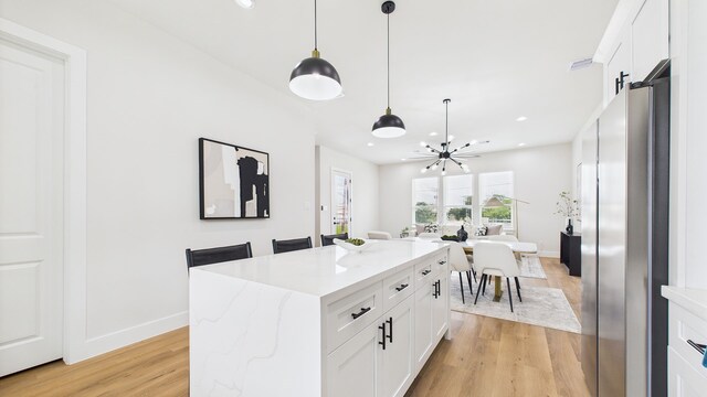 1813 Brooks St, Houston, TX 77026 - kitchen with freestanding refrigerator, light wood-style flooring, a chandelier, white cabinets, and baseboards
