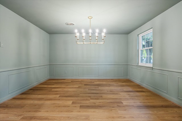 10715 Piping Rock Ln, Houston, TX 77042 - unfurnished dining area with a chandelier, wainscoting, light wood-type flooring, and a decorative wall