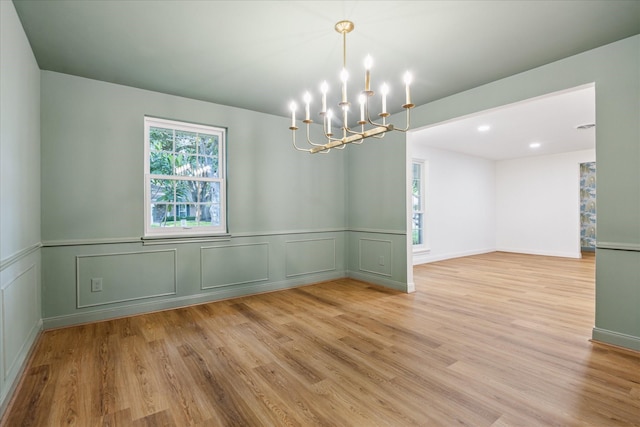 10715 Piping Rock Ln, Houston, TX 77042 - empty room with a chandelier, light wood-style flooring, a decorative wall, and wainscoting