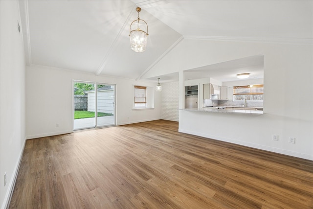 10715 Piping Rock Ln, Houston, TX 77042 - unfurnished living room featuring vaulted ceiling, a chandelier, baseboards, wood finished floors, and a sink