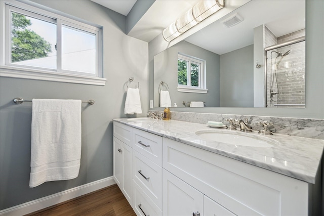 10715 Piping Rock Ln, Houston, TX 77042 - bathroom with double vanity, a tile shower, wood finished floors, and baseboards