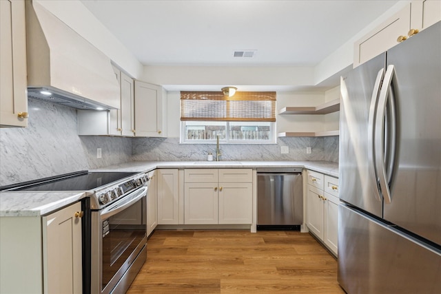 10715 Piping Rock Ln, Houston, TX 77042 - kitchen with appliances with stainless steel finishes, wall chimney range hood, a sink, open shelves, and light wood-style floors