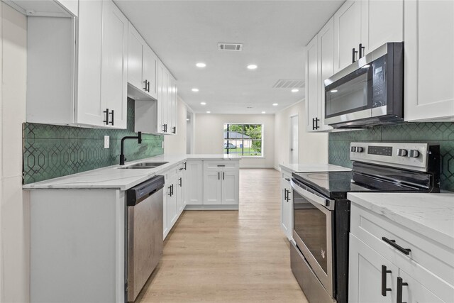 3805 19th St N, Texas City, TX 77590 - kitchen with appliances with stainless steel finishes, a sink, light wood-type flooring, light stone counters, and white cabinetry