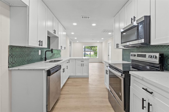 3805 19th St N, Texas City, TX 77590 - kitchen with appliances with stainless steel finishes, light wood-style floors, light stone counters, white cabinets, and a peninsula