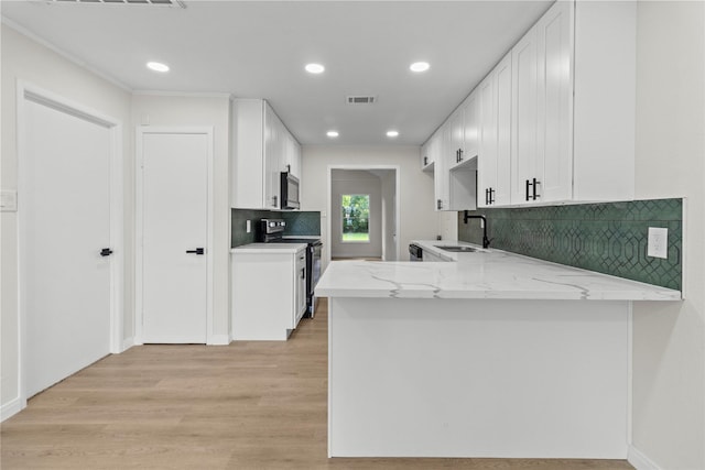3805 19th St N, Texas City, TX 77590 - kitchen with appliances with stainless steel finishes, a sink, light stone countertops, a peninsula, and light wood-type flooring