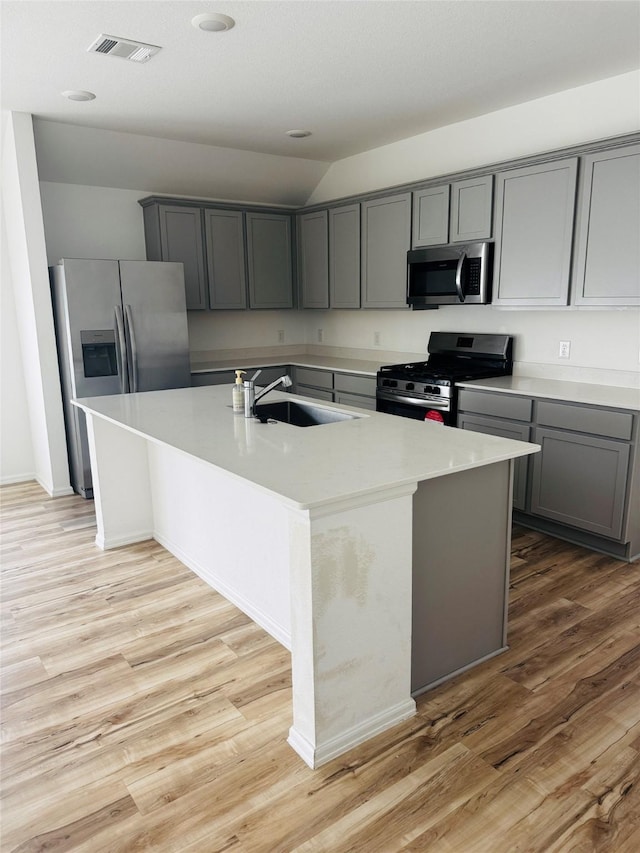 3713 NE River Sand Rd, Rosenberg, TX 77469 - kitchen featuring stainless steel appliances, gray cabinetry, a sink, a kitchen island with sink, and light wood finished floors