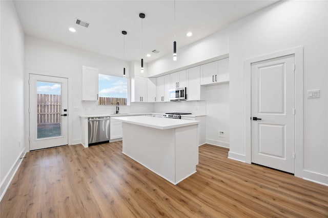 7719 Orebo St, Houston, TX 77088 - kitchen featuring appliances with stainless steel finishes, white cabinets, tasteful backsplash, light wood finished floors, and a center island