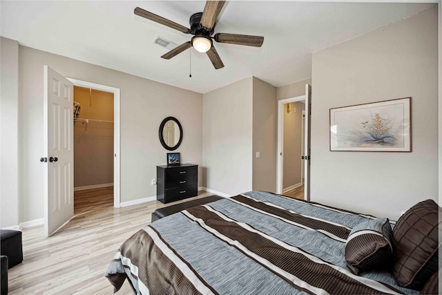 16019 Juniper Grove Dr, Houston, TX 77084 - bedroom with light wood-style flooring, baseboards, ceiling fan, a walk in closet, and a closet