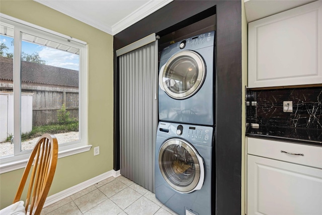 16019 Juniper Grove Dr, Houston, TX 77084 - washroom featuring stacked washer / dryer, light tile patterned floors, ornamental molding, plenty of natural light, and baseboards
